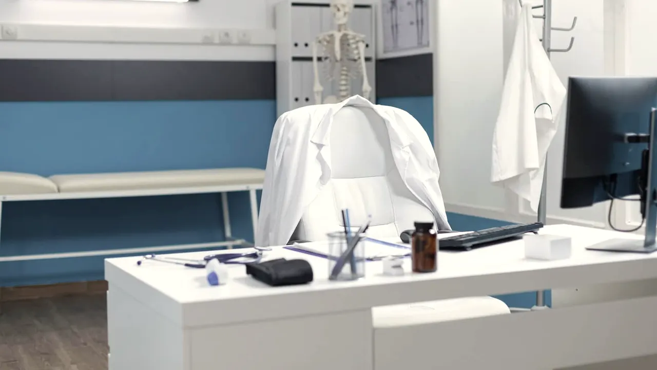 Mesa de consultório com computador, pronta para uma consulta por vídeo.