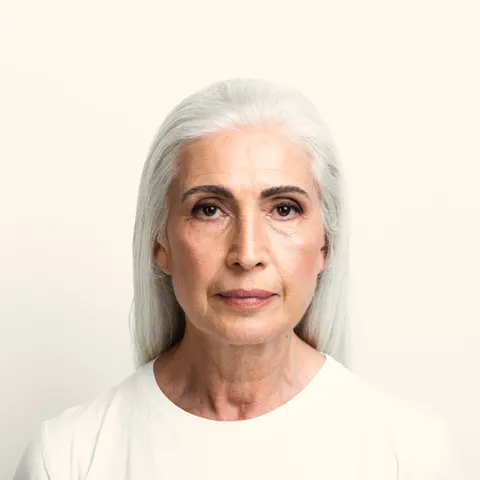 Mulher de cabelos grisalhos com expressão serena, retrato frontal.