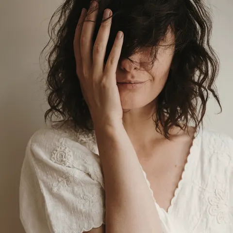 Mulher adulta jovem com sorriso suave, retrato em tom bege.